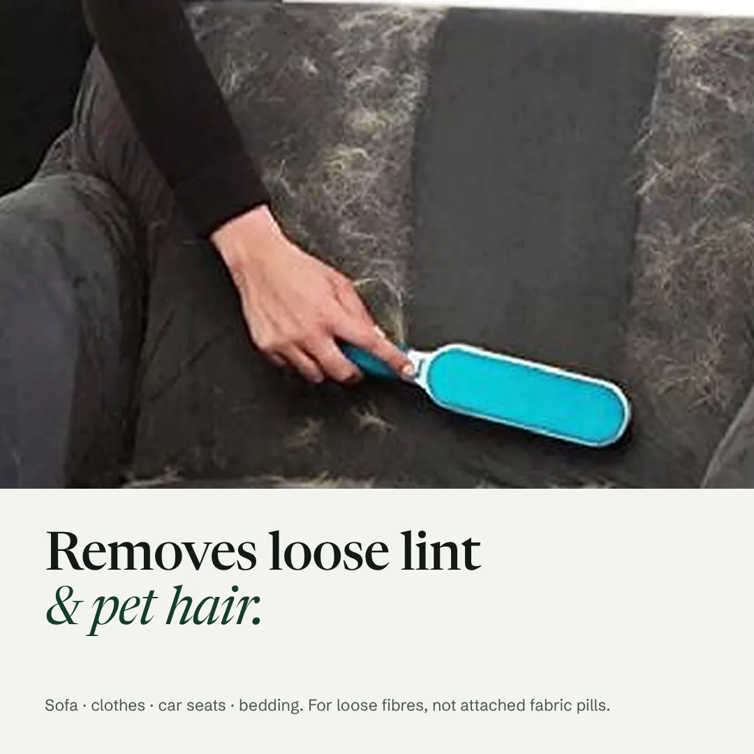 Loose pet hair being brushed off a grey sofa, with a clean stripe where the brush has passed